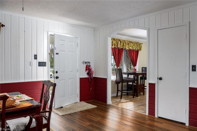 foyer entrance featuring wood-type flooring, a textured ceiling, and crown molding