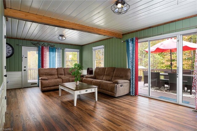 living room with dark wood-type flooring, wooden walls, beam ceiling, and wooden ceiling