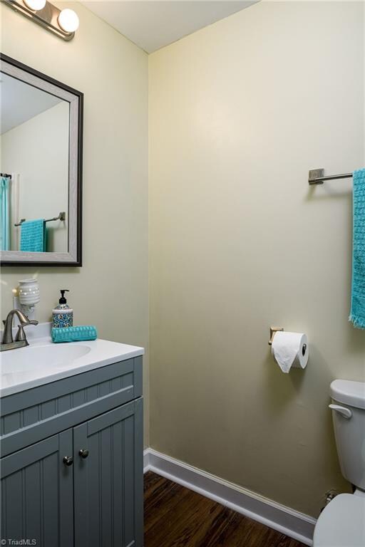 bathroom featuring wood-type flooring, vanity, and toilet