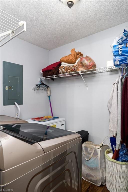 laundry area featuring washer and clothes dryer, electric panel, a textured ceiling, and hardwood / wood-style flooring