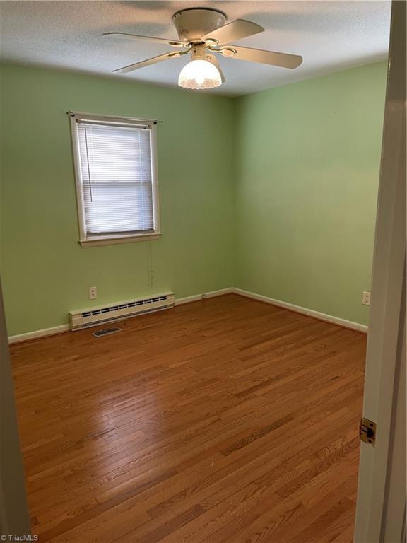 139 Orchard View Dr, Mount Airy, NC 27030 - unfurnished room featuring baseboards, baseboard heating, a ceiling fan, and wood finished floors