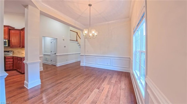 5567 Foxgate Cir, Winston-Salem, NC 27106 - unfurnished dining area featuring light wood-style flooring, crown molding, a chandelier, a wainscoted wall, and ornate columns