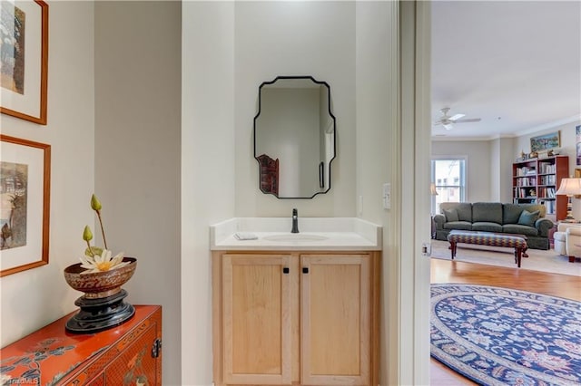 bathroom featuring a ceiling fan, wood finished floors, vanity, and crown molding