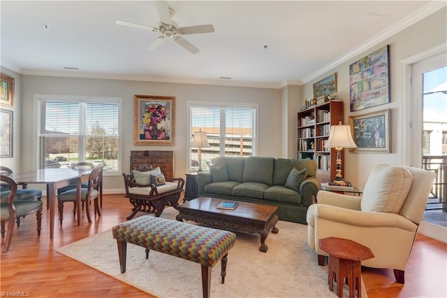 living room featuring ceiling fan, baseboards, light wood finished floors, and ornamental molding