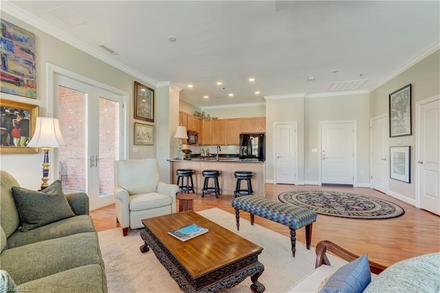 living area with visible vents, light wood finished floors, baseboards, french doors, and crown molding