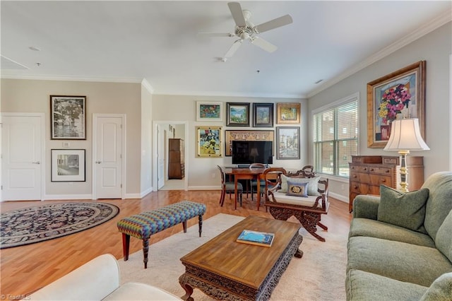 living area with a ceiling fan, crown molding, baseboards, and wood finished floors