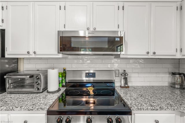 2664 Old Thomasville Rd, Winston-Salem, NC 27107 - kitchen with stainless steel appliances, white cabinets, decorative backsplash, and light stone countertops