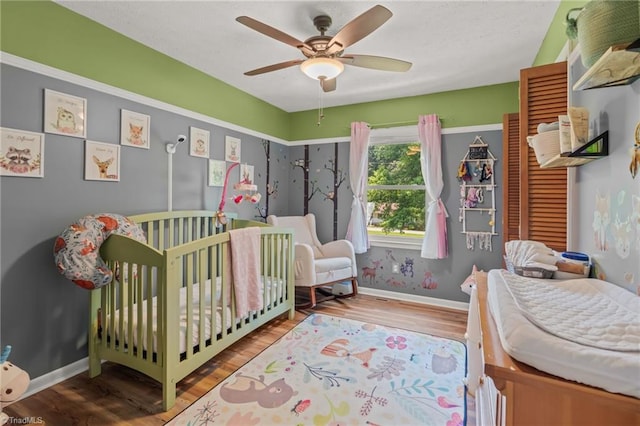 2664 Old Thomasville Rd, Winston-Salem, NC 27107 - bedroom with a crib, wood finished floors, and ceiling fan