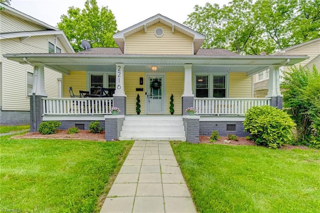 bungalow-style home with a porch, a front yard, and roof with shingles