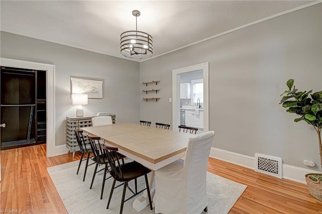dining space featuring light wood-style floors, a chandelier, and baseboards