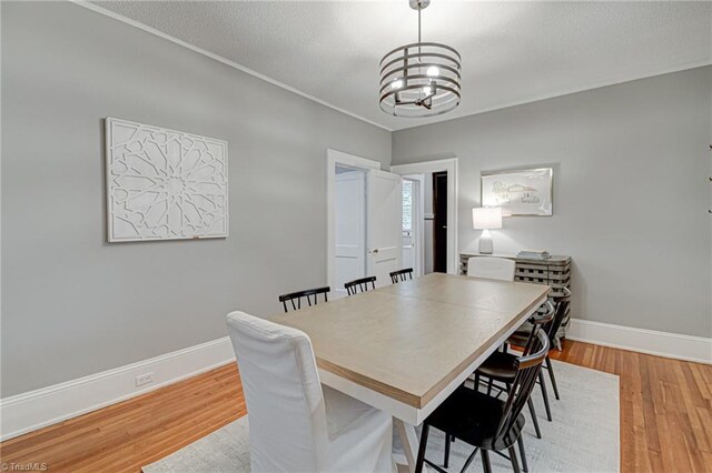 dining area featuring a chandelier, light wood-type flooring, and baseboards