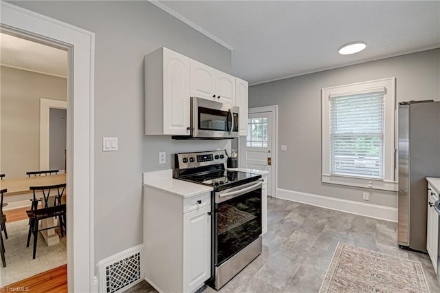 kitchen with appliances with stainless steel finishes, white cabinetry, ornamental molding, light countertops, and baseboards