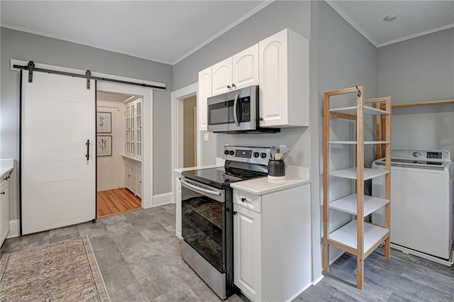 kitchen with washer / dryer, stainless steel appliances, a barn door, white cabinets, and light countertops