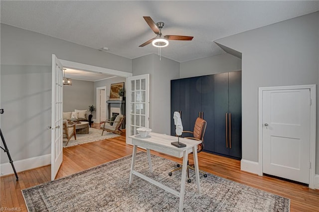 home office featuring french doors, wood finished floors, baseboards, and a ceiling fan