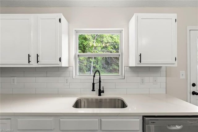 kitchen featuring a sink, decorative backsplash, white cabinets, and stainless steel dishwasher