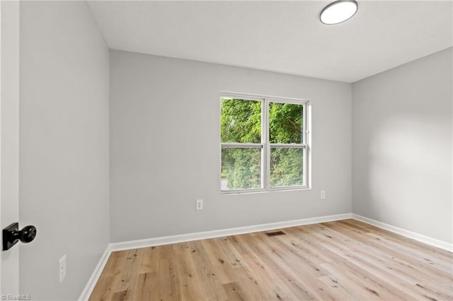 spare room featuring baseboards, light wood-type flooring, and visible vents