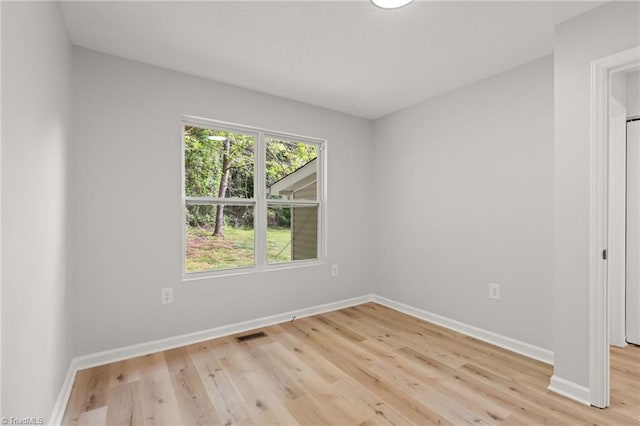 spare room with baseboards, light wood-style flooring, and visible vents