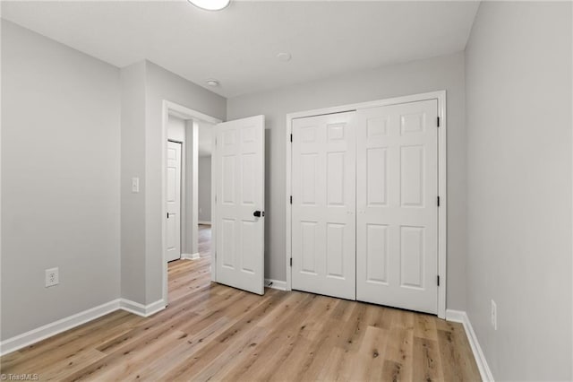unfurnished bedroom featuring a closet, baseboards, and light wood-style floors