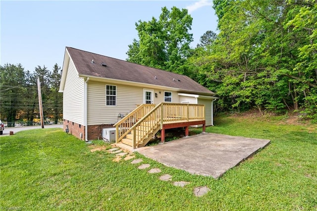 rear view of house featuring a yard, crawl space, a wooden deck, and a patio area
