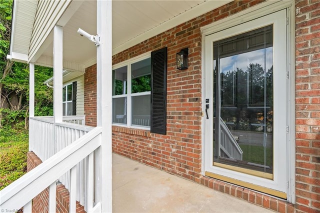 doorway to property with covered porch and brick siding