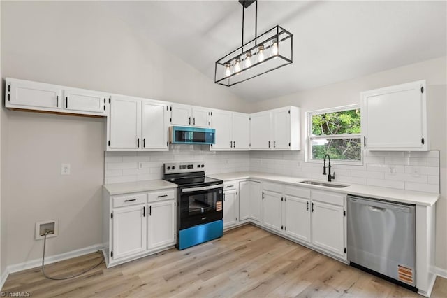 kitchen with backsplash, vaulted ceiling, a sink, stainless steel appliances, and white cabinetry