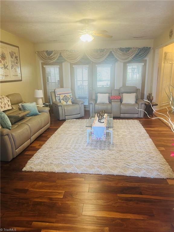 living room featuring dark wood-type flooring and ceiling fan