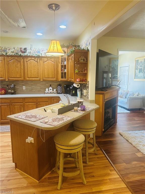 kitchen with light wood finished floors, a breakfast bar, brown cabinetry, and decorative backsplash