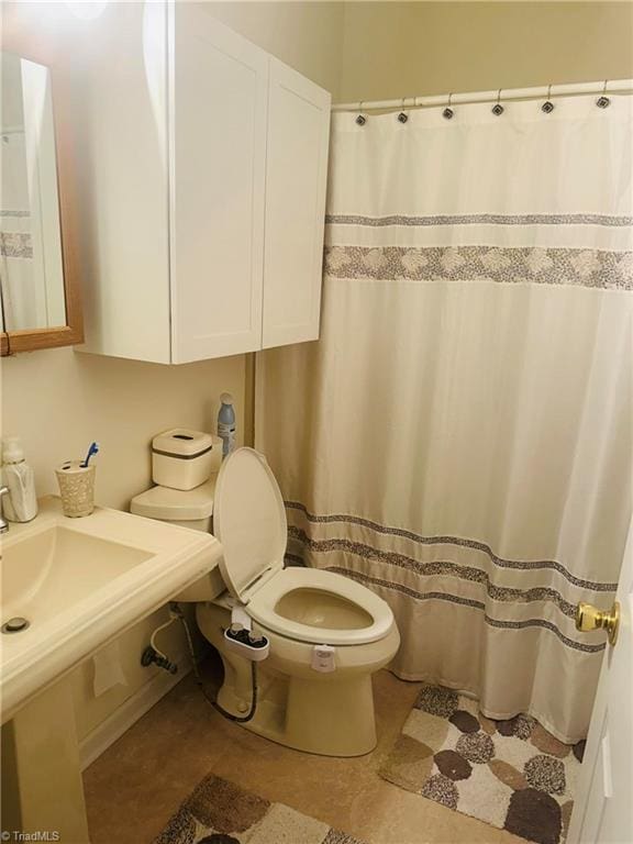 bathroom featuring tile patterned floors, toilet, and a shower with curtain