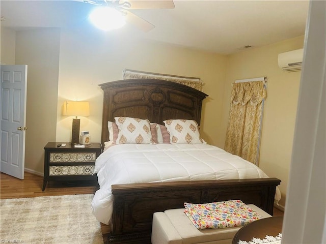 bedroom with a ceiling fan, a wall mounted AC, and wood finished floors