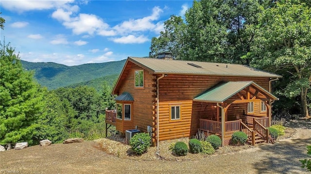 exterior space with metal roof, central AC unit, a mountain view, covered porch, and a chimney