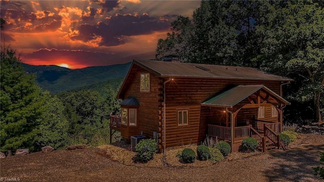 exterior space featuring a porch, central AC, metal roof, a mountain view, and log exterior