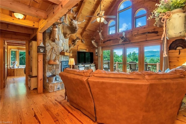 living room featuring wooden walls, wood ceiling, ceiling fan, wood finished floors, and a fireplace