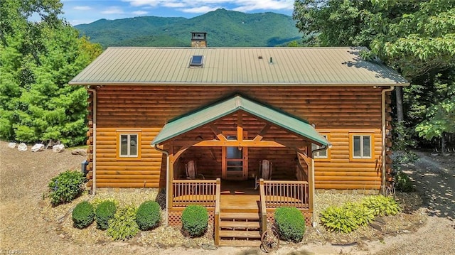 back of property featuring a chimney, a mountain view, log exterior, and metal roof