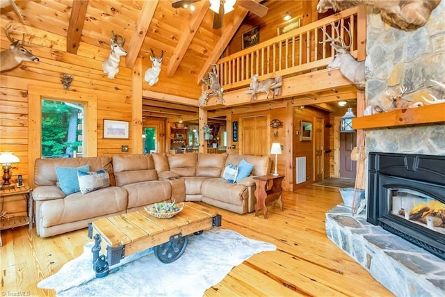 living room featuring hardwood / wood-style flooring, wood walls, visible vents, and beamed ceiling