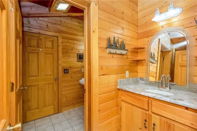 bathroom with toilet, wooden walls, vanity, and tile patterned floors