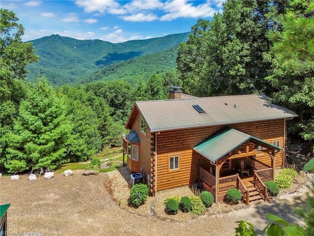 exterior space with a chimney, dirt driveway, central AC unit, metal roof, and a mountain view