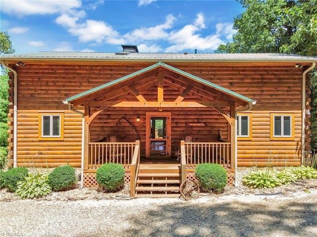 cabin featuring covered porch, log exterior, and a chimney