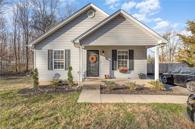 bungalow with a front lawn, fence, and covered porch