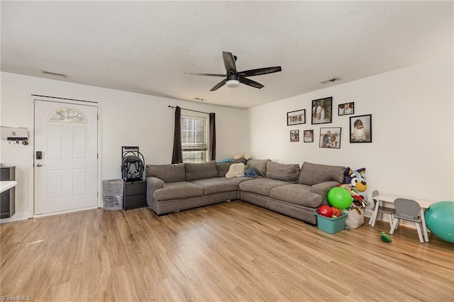 living room with visible vents, a textured ceiling, light wood-type flooring, and ceiling fan