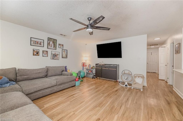 living area with a textured ceiling, light wood-style floors, and ceiling fan