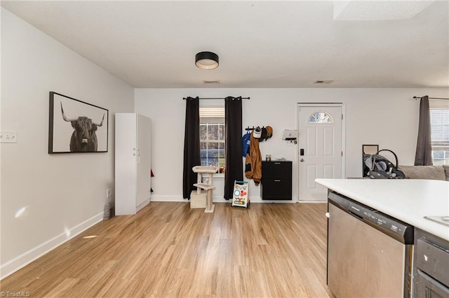 kitchen featuring baseboards, visible vents, light countertops, light wood-style floors, and dishwasher