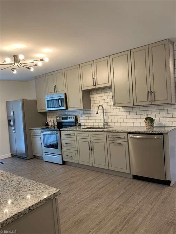 kitchen featuring stainless steel appliances, sink, decorative backsplash, and light hardwood / wood-style flooring