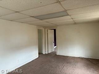 unfurnished room featuring baseboards, a drop ceiling, and carpet flooring