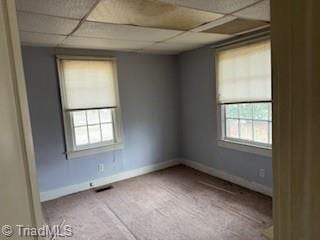 empty room with carpet floors, a paneled ceiling, visible vents, and baseboards