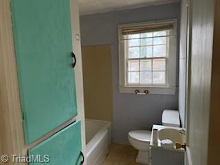 bathroom with a tub to relax in, vanity, and toilet