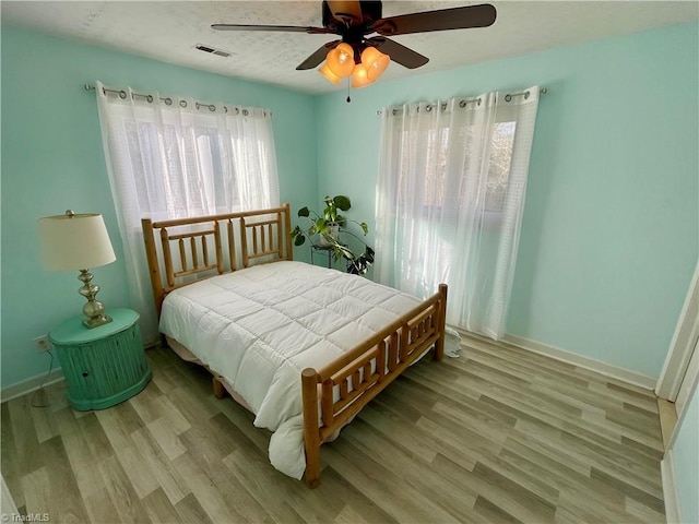 bedroom with ceiling fan, light hardwood / wood-style flooring, and a textured ceiling