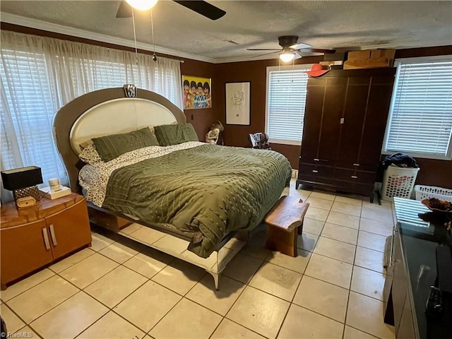 bedroom featuring ceiling fan, multiple windows, ornamental molding, a textured ceiling, and light tile patterned flooring