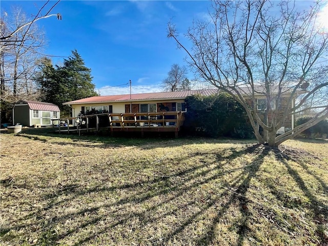 back of house with a wooden deck, a lawn, and a shed