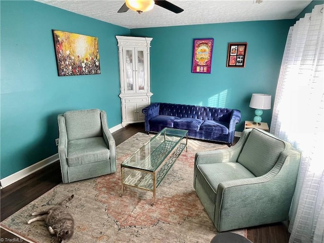 living room with hardwood / wood-style flooring, ceiling fan, and a textured ceiling