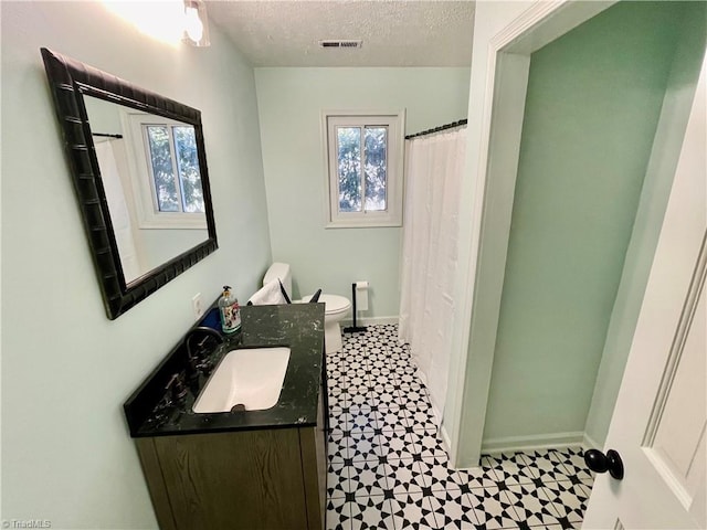 bathroom with vanity, toilet, and a textured ceiling